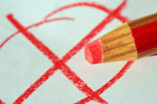 Roter Buntstift auf Papier mit handgezeichnetem roten Kreuz innerhalb eines Kreises.