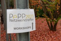 Schild mit PePP 2023 Netzwerktreffen WORKSHOPS vor herbstlichen Bäumen. Pfeil weist den Weg zu den Workshops.