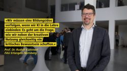 Ein lächelnder Mann steht in einem modernen Gebäude. Zitat von ihm, Prof. DR. Rudolf Kammerl, FAU Erlangen-Nürnberg: "Wir müssen eine Bildungsidee verfolgen, wenn wir KI in die Lehre einbinden: Es geht um die Frage, wie wir neben der kreativen Nutzung gleichzeitig ein kritisches Bewusstsein schaffen."
