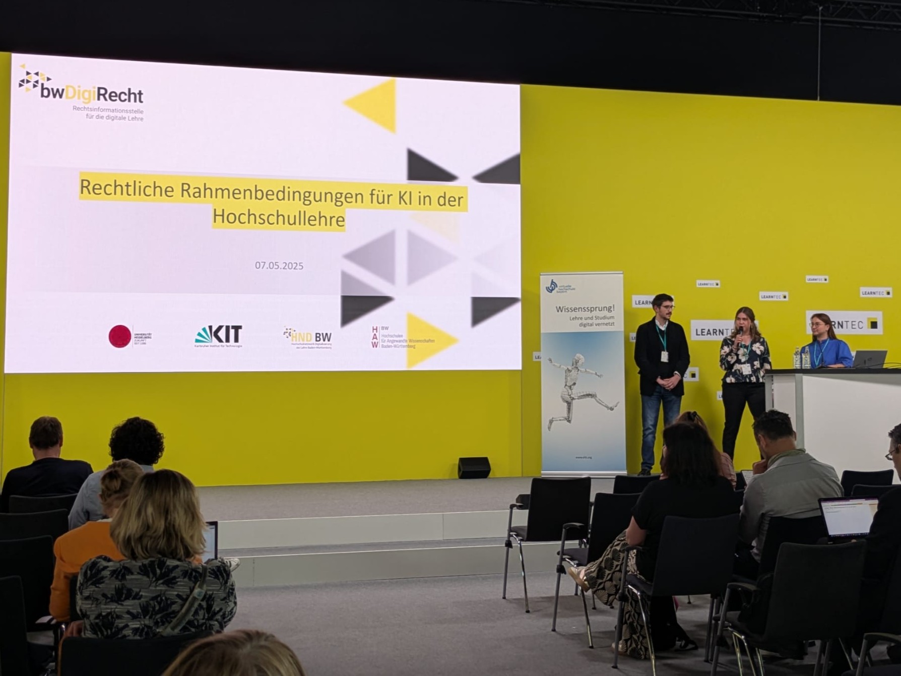 Diskussion über KI-Recht in der Hochschullehre bei bwDigiRecht-Veranstaltung, drei Sprecher vor Publikum.