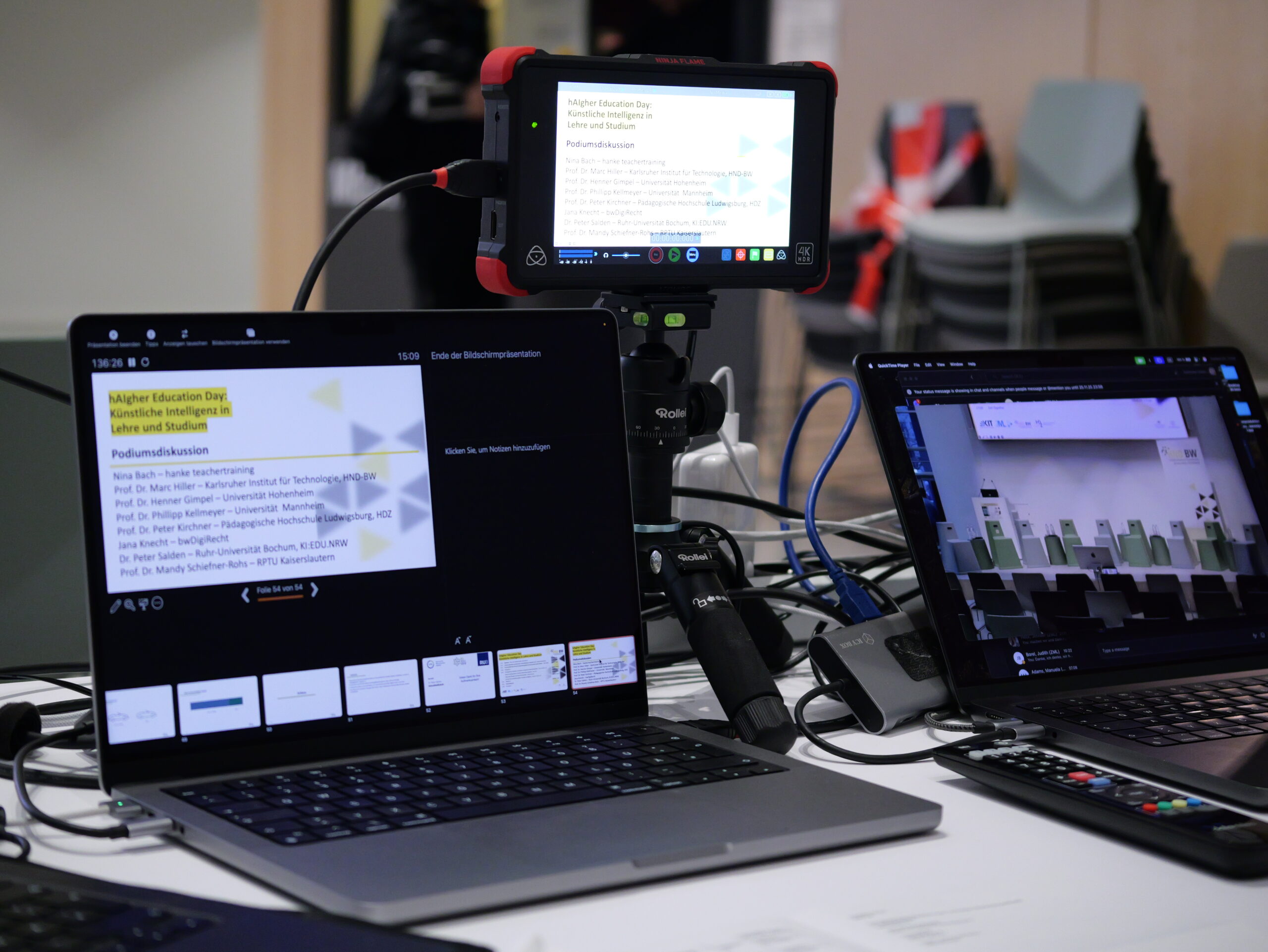 P1002344 Laptops und Monitor zeigen Präsentation über Künstliche Intelligenz in der Lehre. Thema: Podiumsdiskussion.